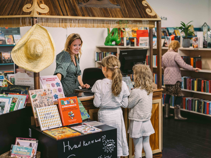 Medarbejder hjælper to piger på børnebiblioteket i Bryggen.
