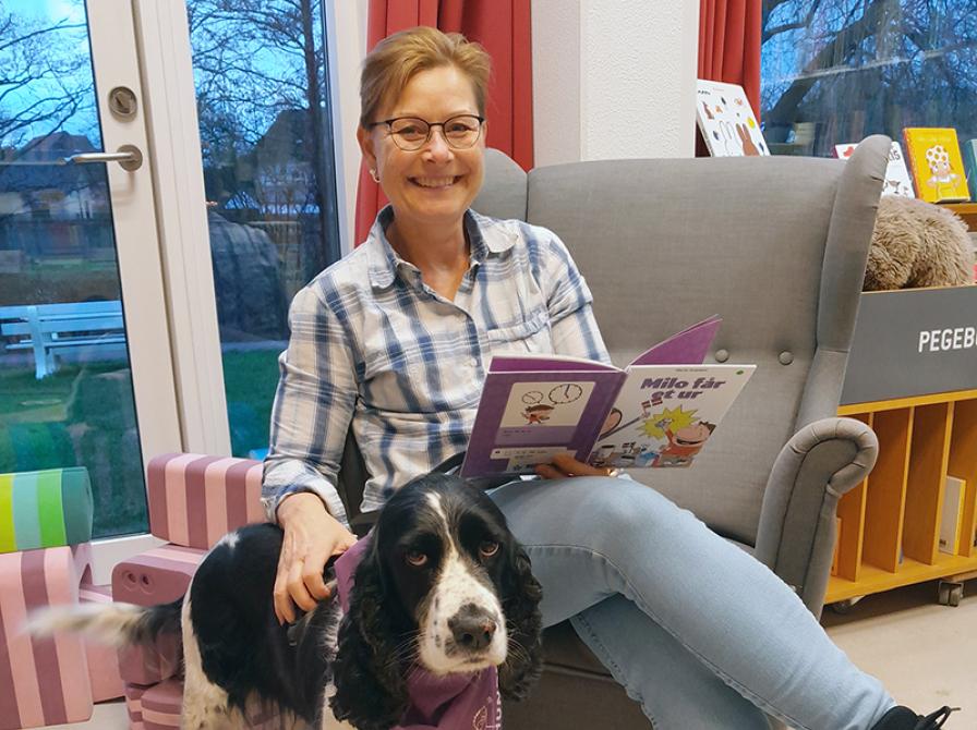 Marie, der sidder og læser, med sin læsehund Sally